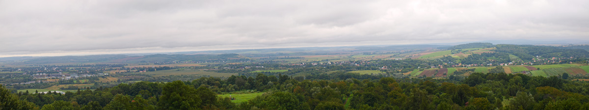 Panoramatický pohled z Tatarského kopce jihovýchodním směrem. Zalesněné výšiny vlevo od středu snímku skrývají siedliskou skupinu fortů, o níž se během prvního obležení vedly nejzuřivější boje.
