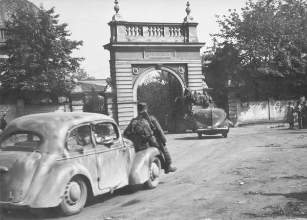 Samohybné dělo Sd.Kfz. 138/1 Grille a další vozidla poslední německé kolony projíždějí branou Nového židovského hřbitova. Hebrejský nápis na vnější straně brány praví: „Prach jsi a v prach se obrátíš.“ Vzhledem k tomu, že v této koloně opouštěl Prahu i poslední velitel Waffen-SS v Čechách a na Moravě, SS-Gruppenführer Karl von Pückler-Burghaus, dostává celá scéna takřka kafkovský nádech. 
FOTO: Oldřich Cerha
