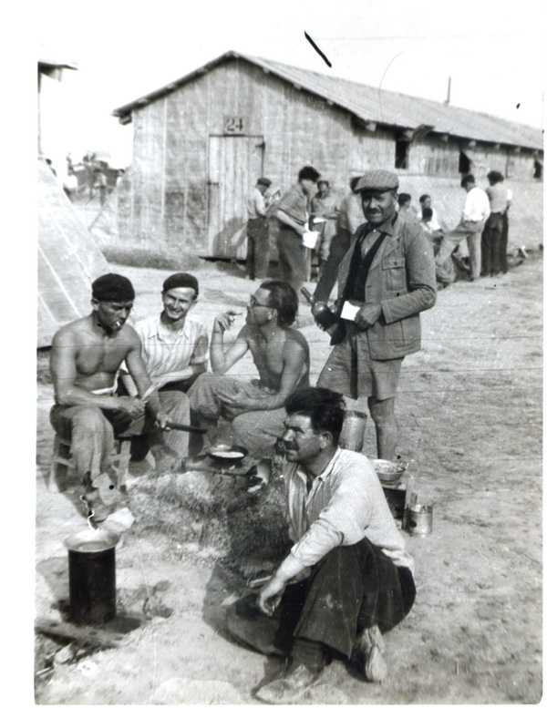 Foto z internačního tábora Gurs z léta 1939. Hoffmann sedí u ohně (v brýlích).