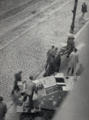 Štábní praporčík vládního vojska Bohuslav Sudík je 5. května 1945 odpoledne odnášen ze svého stroje na nosítkách patrně na blízkou Záchrannou stanici 7 pražské Luftschutzpolizei na Královské třídě č. 49/83. 
(FOTO: VHÚ Praha, XIX-45263)
